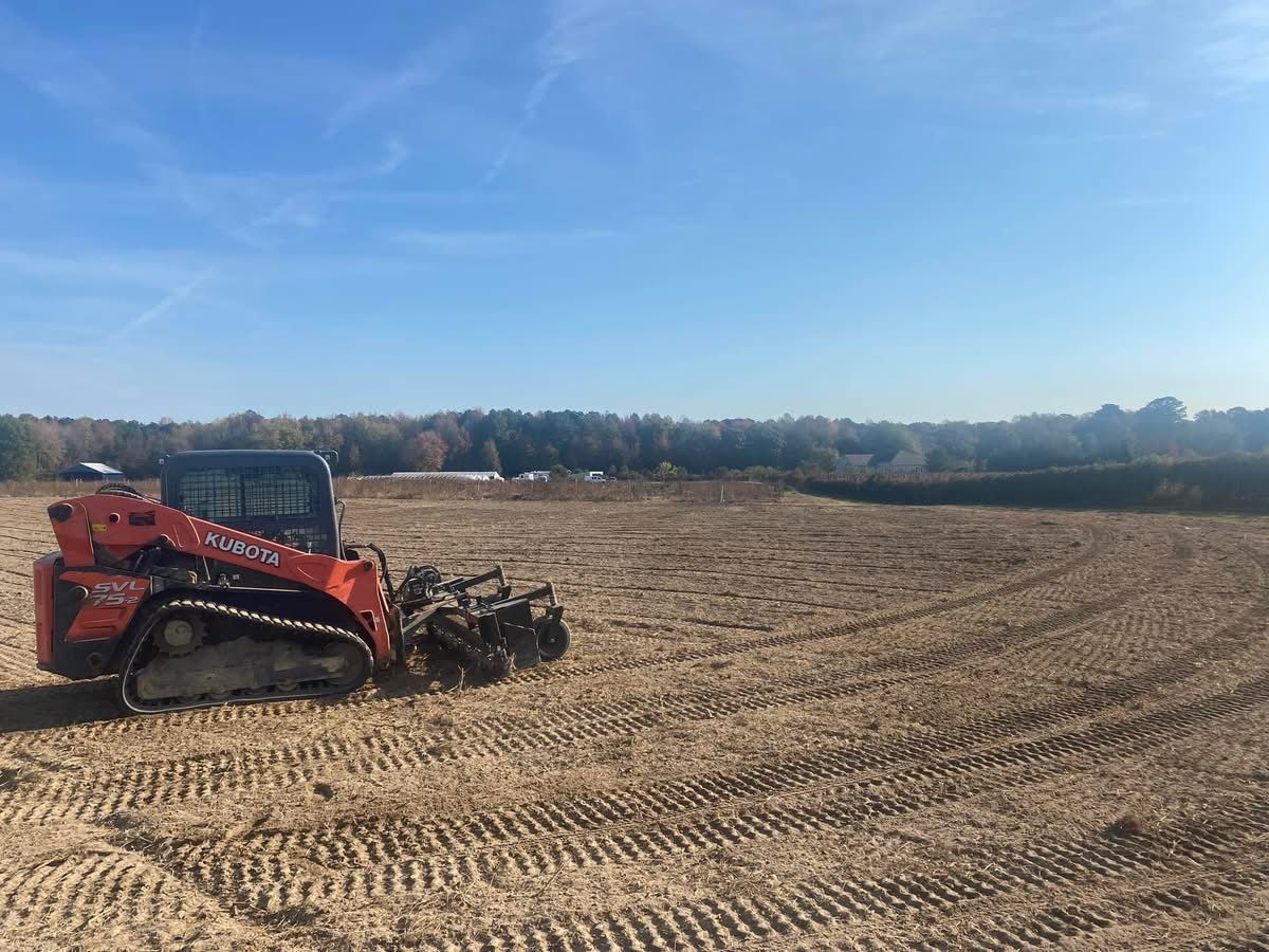 A red bulldozer is driving through a dirt field.