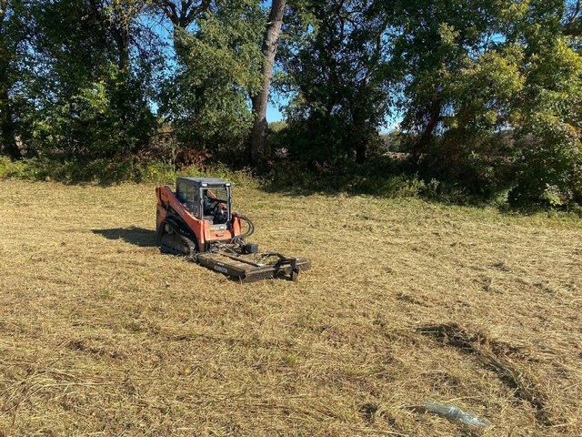 A small red tractor is sitting in the middle of a field.