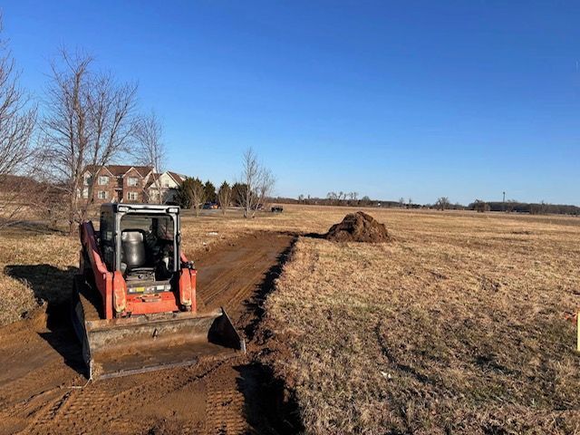 A bulldozer is driving down a dirt road in a field.