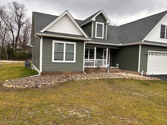 A green and white house with a gray roof and a white garage door.