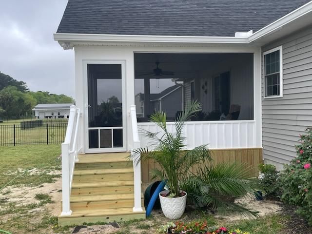 A screened in porch on the side of a house.