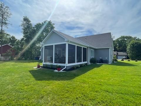 A house with a screened in porch in the backyard.