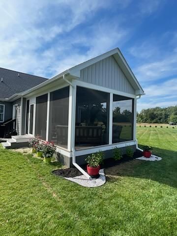 There is a screened in porch in the backyard of a house.