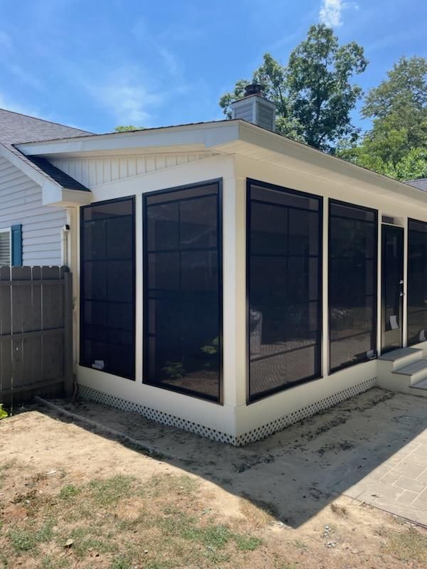 A house with a screened in porch and a fence in the backyard.