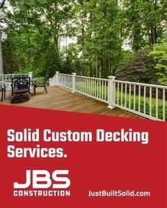 Deck with white railing and patio furniture in a wooded yard, branded Solid Custom Decking Services.