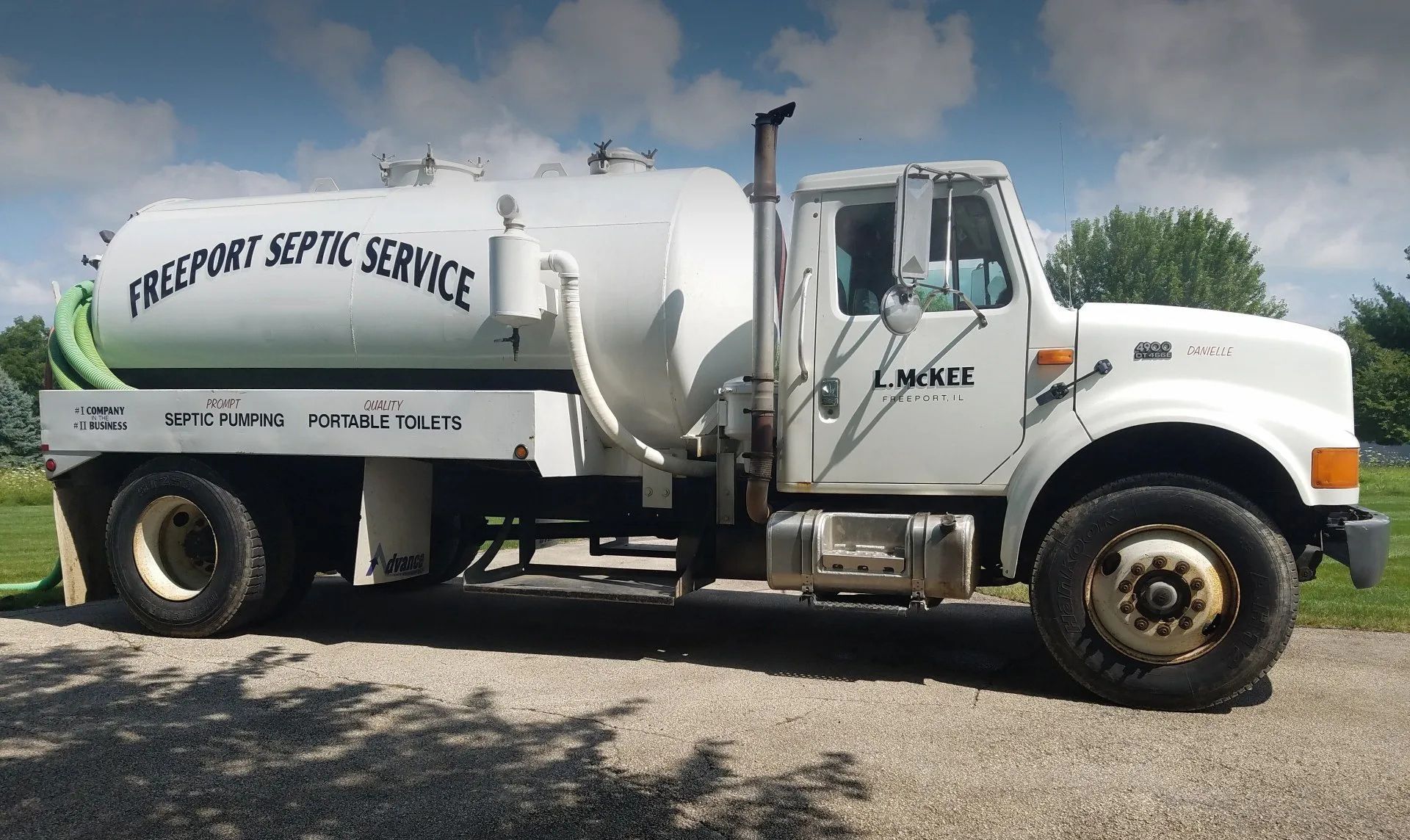 White septic service truck parked outdoors under a blue sky