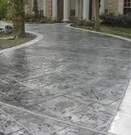 A person is using a tool to spread concrete on a sidewalk