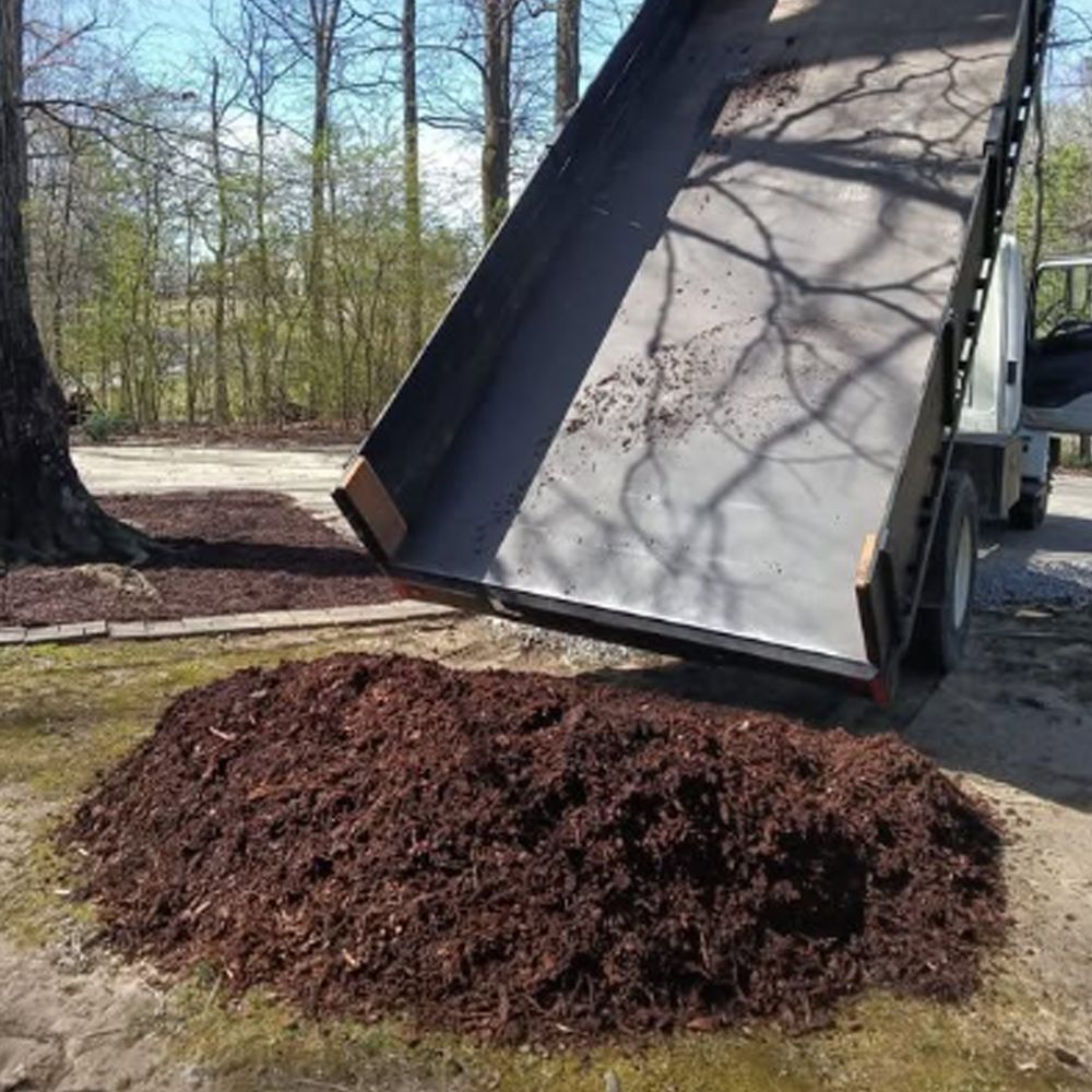 A dump truck is being loaded with brown mulch