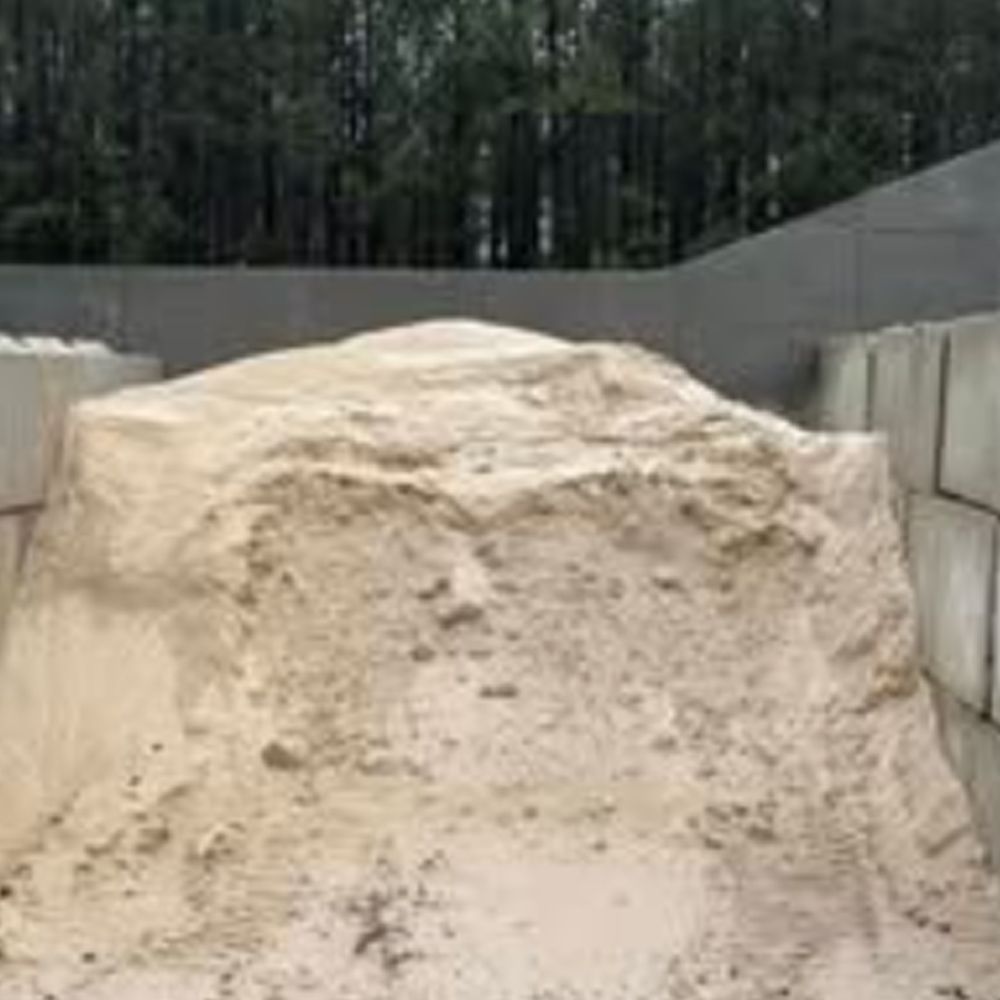 A pile of sand is sitting on top of a pile of concrete blocks.