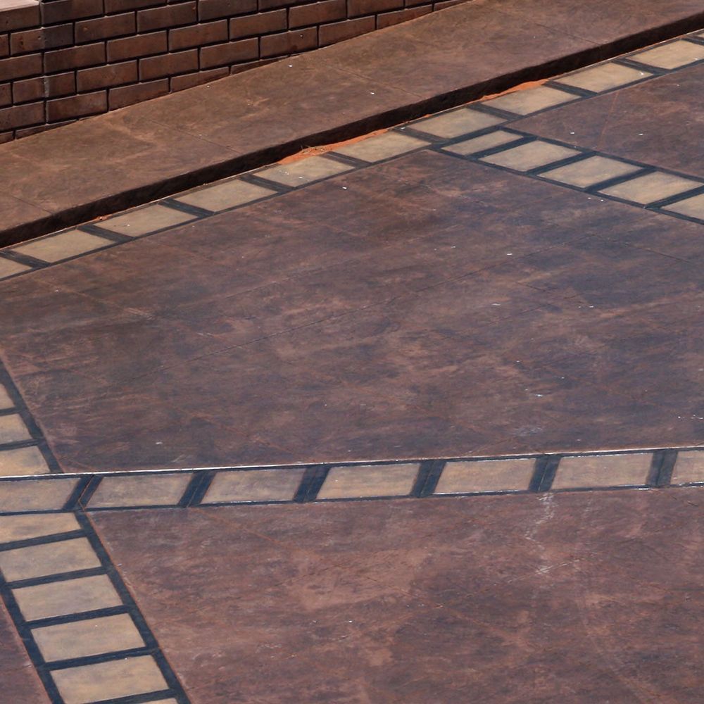 A brown stained concrete floor with a brick wall in the background