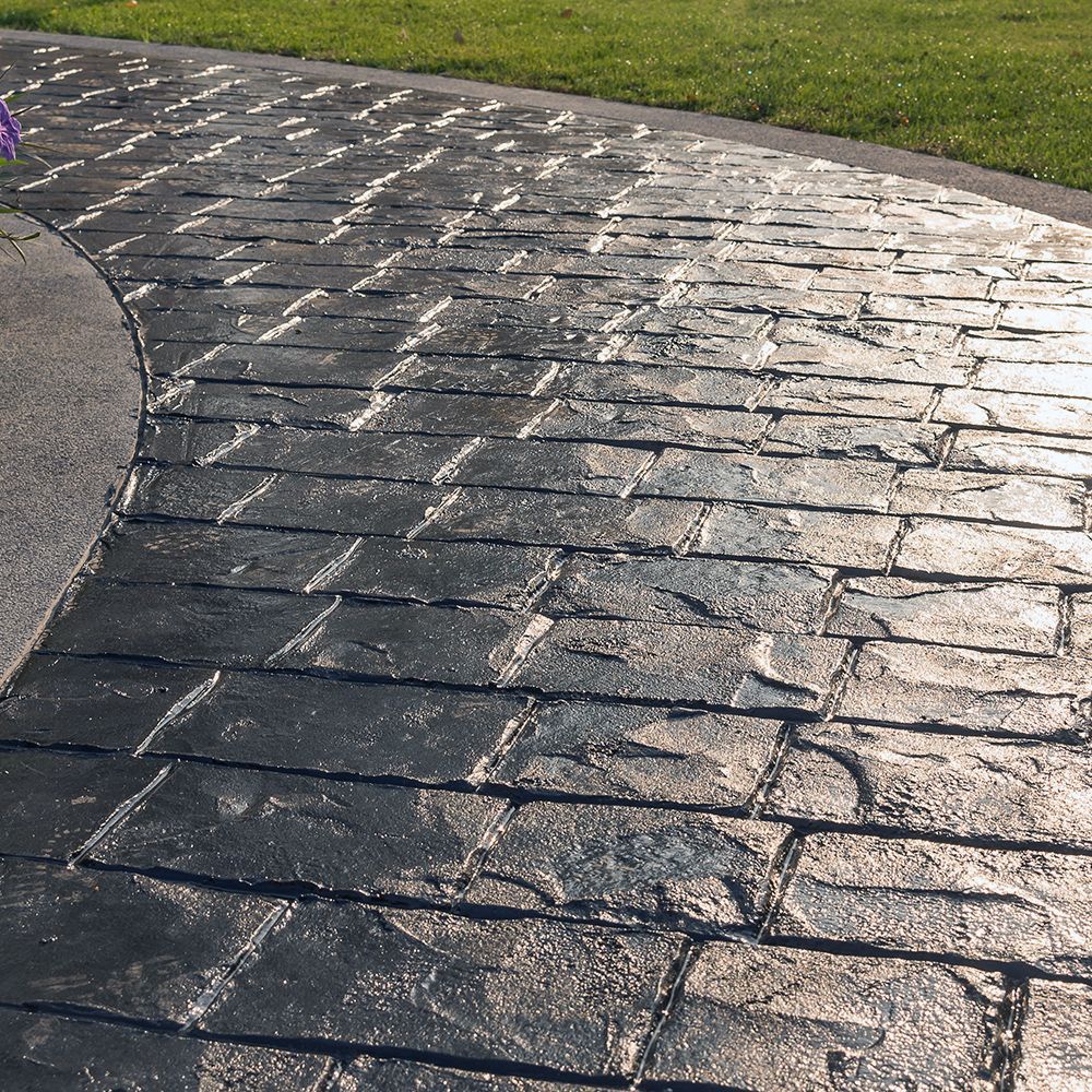 A stamped concrete walkway with grass in the background