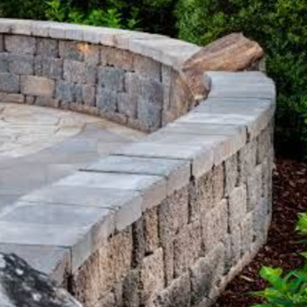 A stone wall with a brick patio in the background.