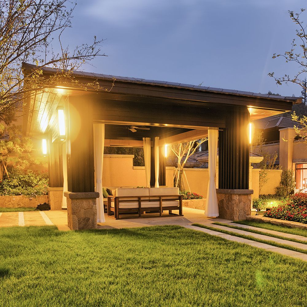 A gazebo with a couch underneath it is lit up at night.