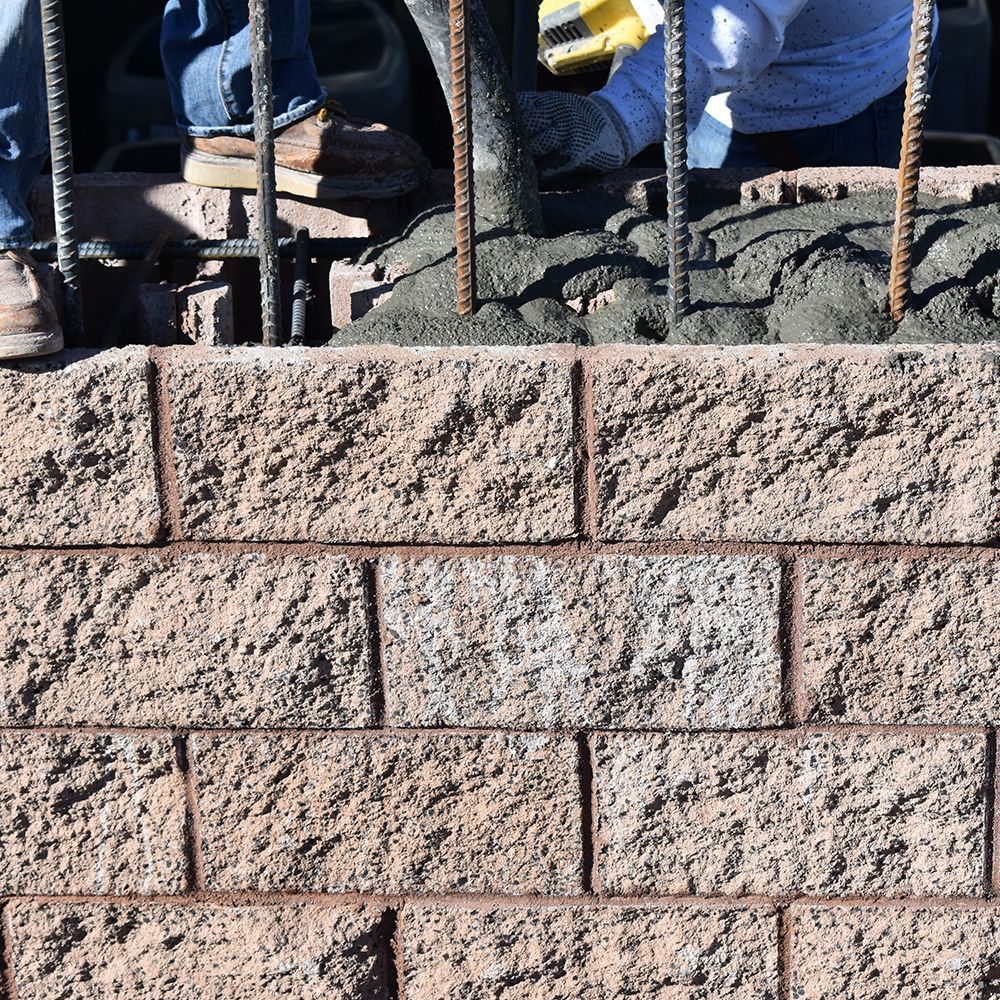 A person is laying concrete on a brick wall
