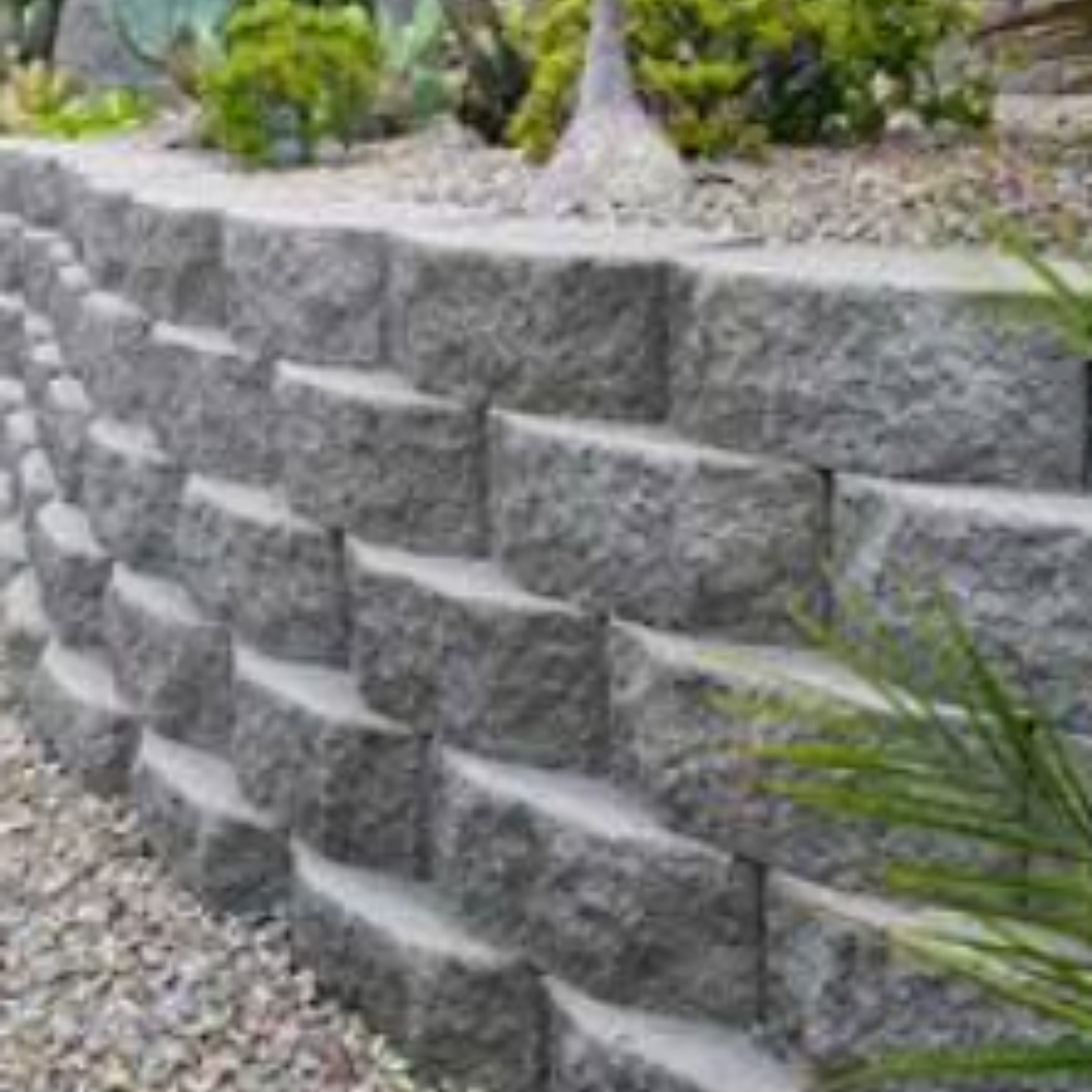 A stone wall surrounded by gravel and plants in a garden.