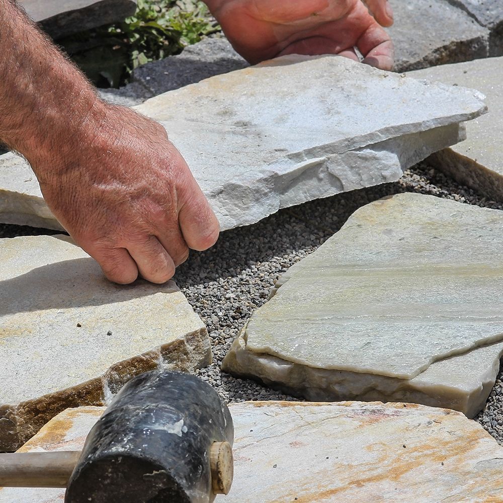A person is using a hammer to hammer a piece of stone.