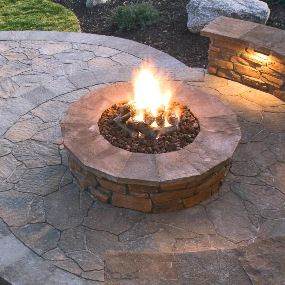 A fire pit is lit up on a stone patio