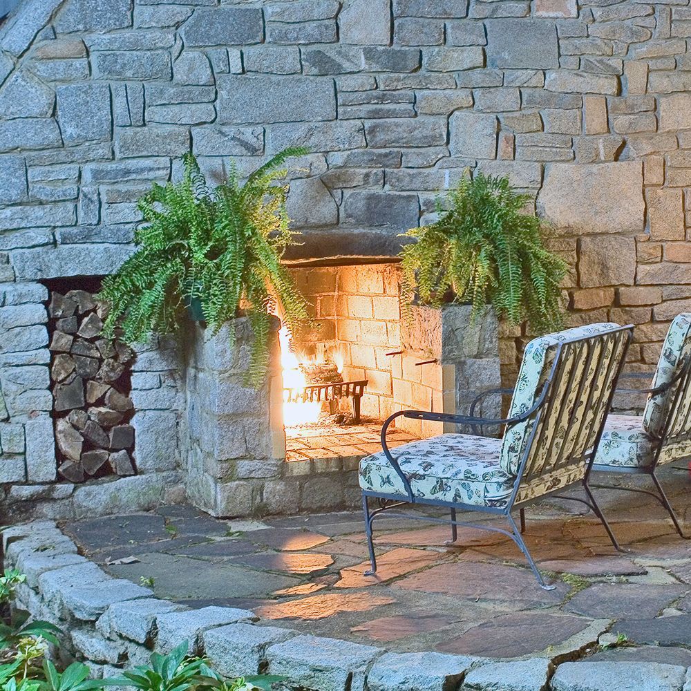 A stone fireplace with two chairs in front of it