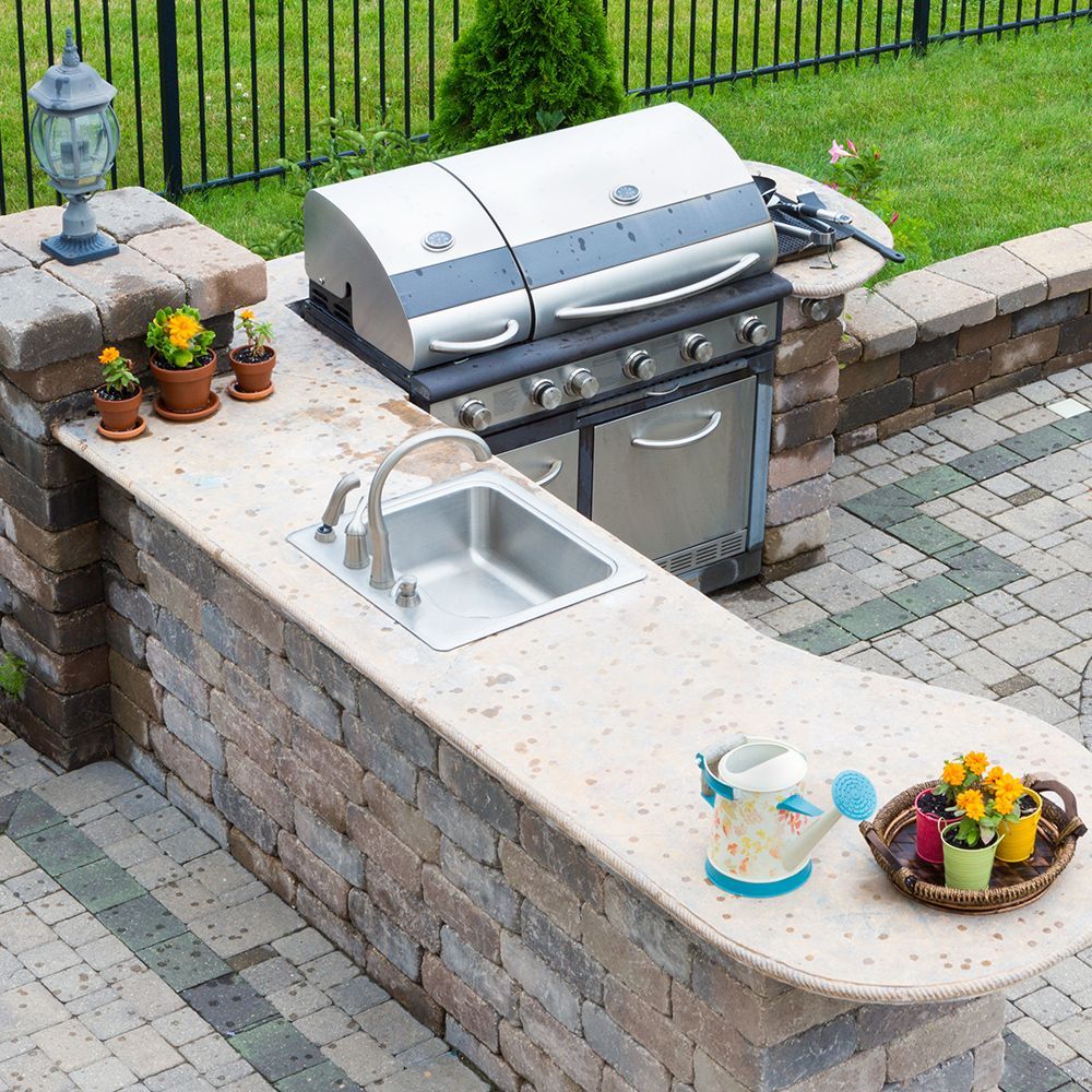 An outdoor kitchen with a grill and a sink
