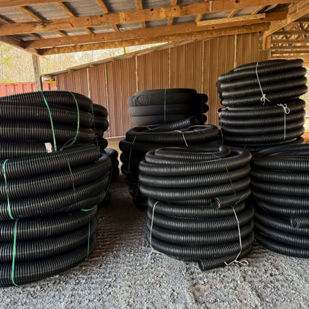 A bunch of black pipes are stacked on top of each other in front of a green truck.