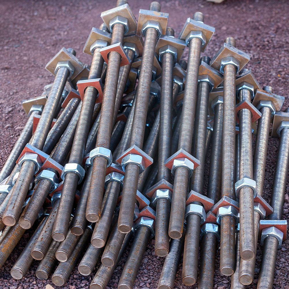 A pile of metal rods with nuts and washers on them