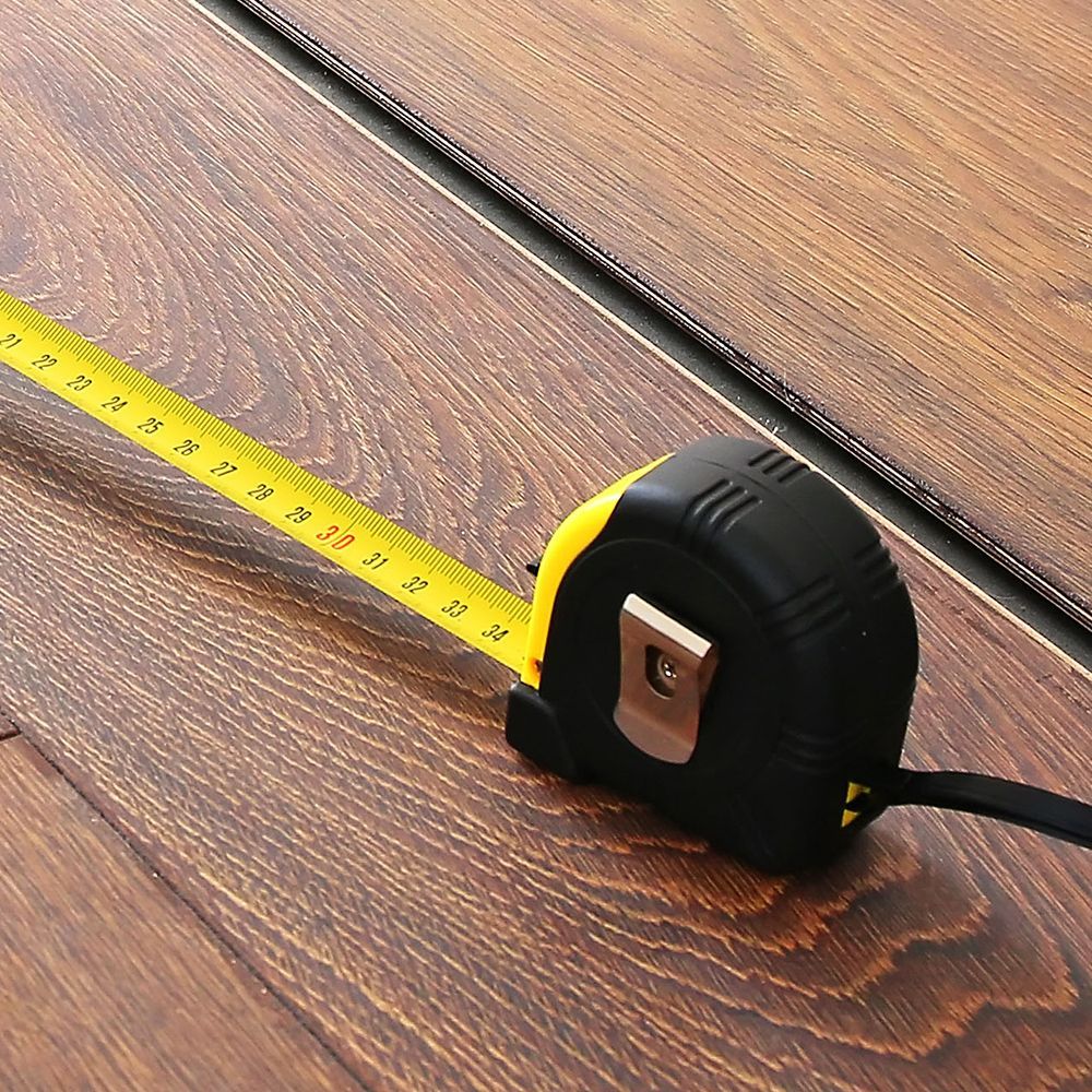 A black and yellow tape measure is on a wooden floor