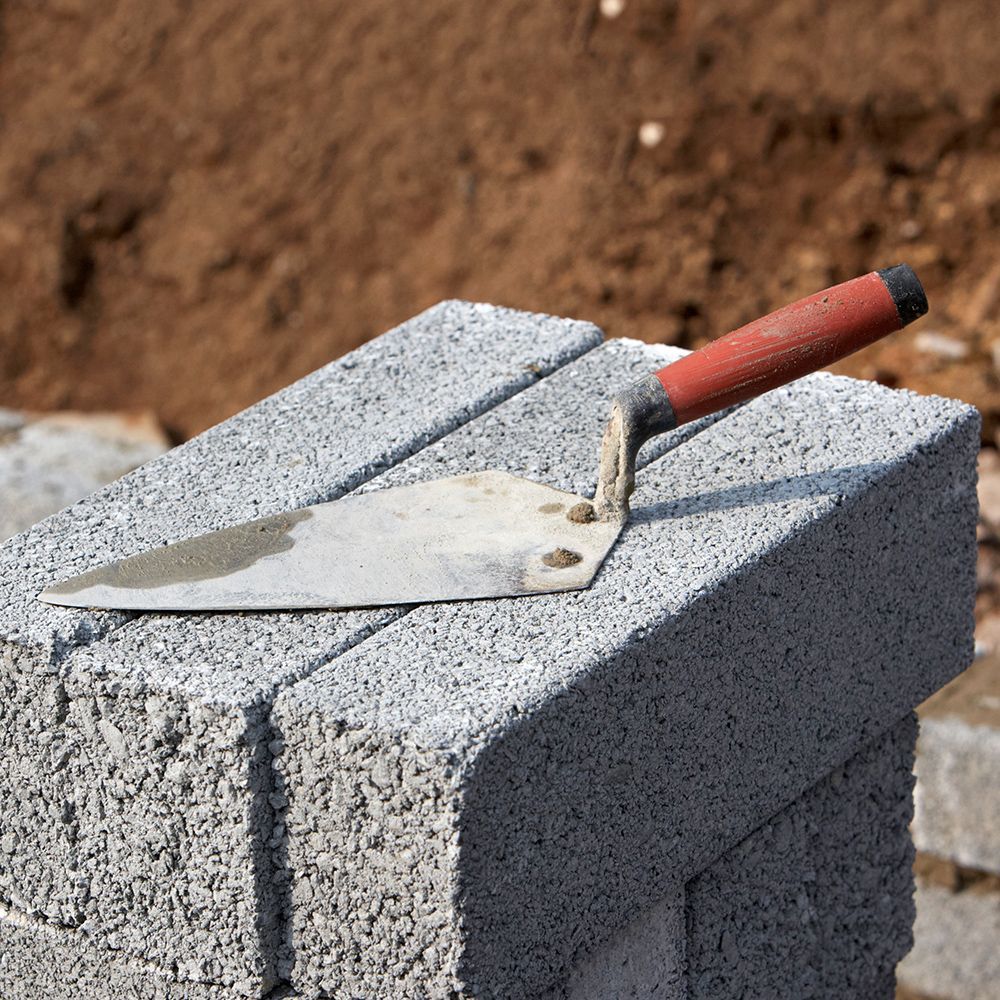 A trowel is sitting on top of a stack of bricks