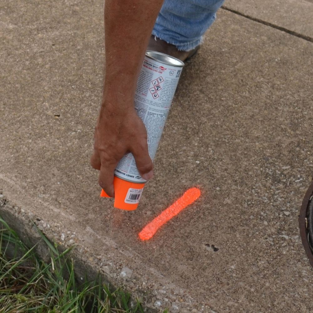 A person is spraying marking paint on a ground