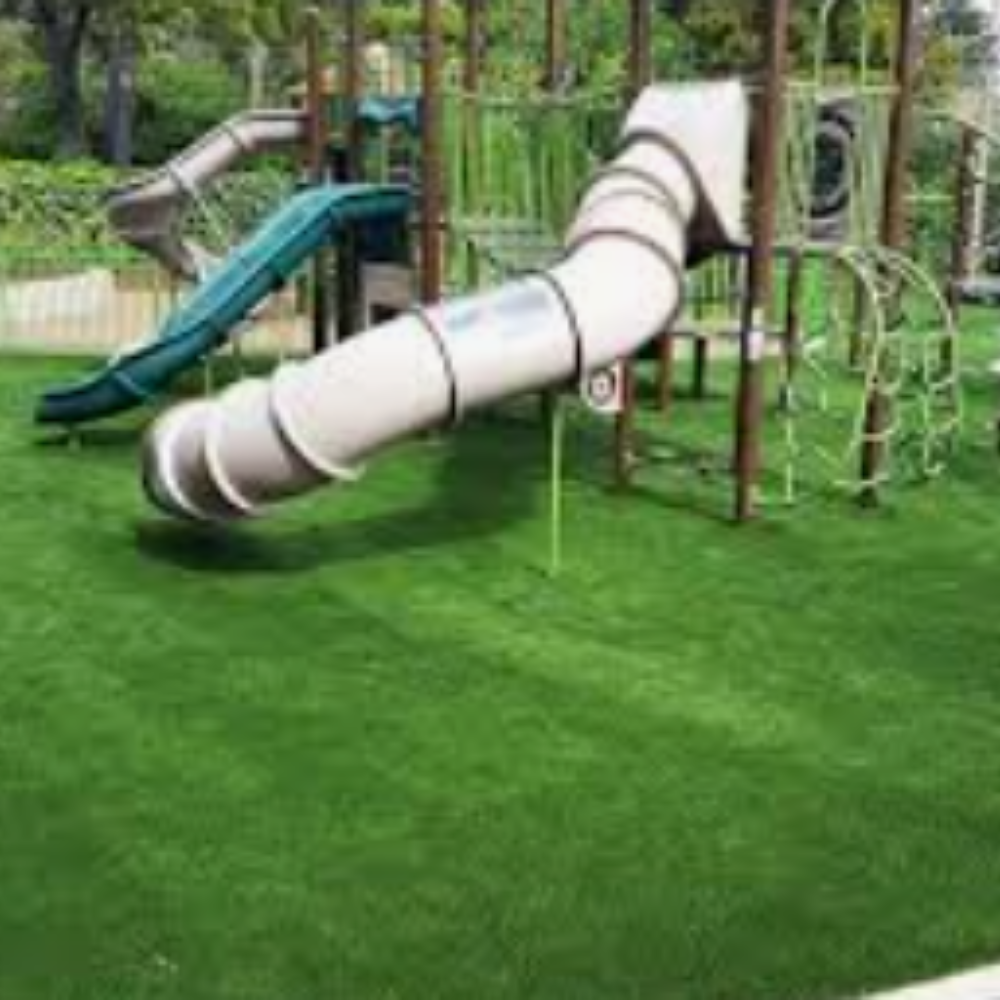A playground with a slide and swings on a lush green field.
