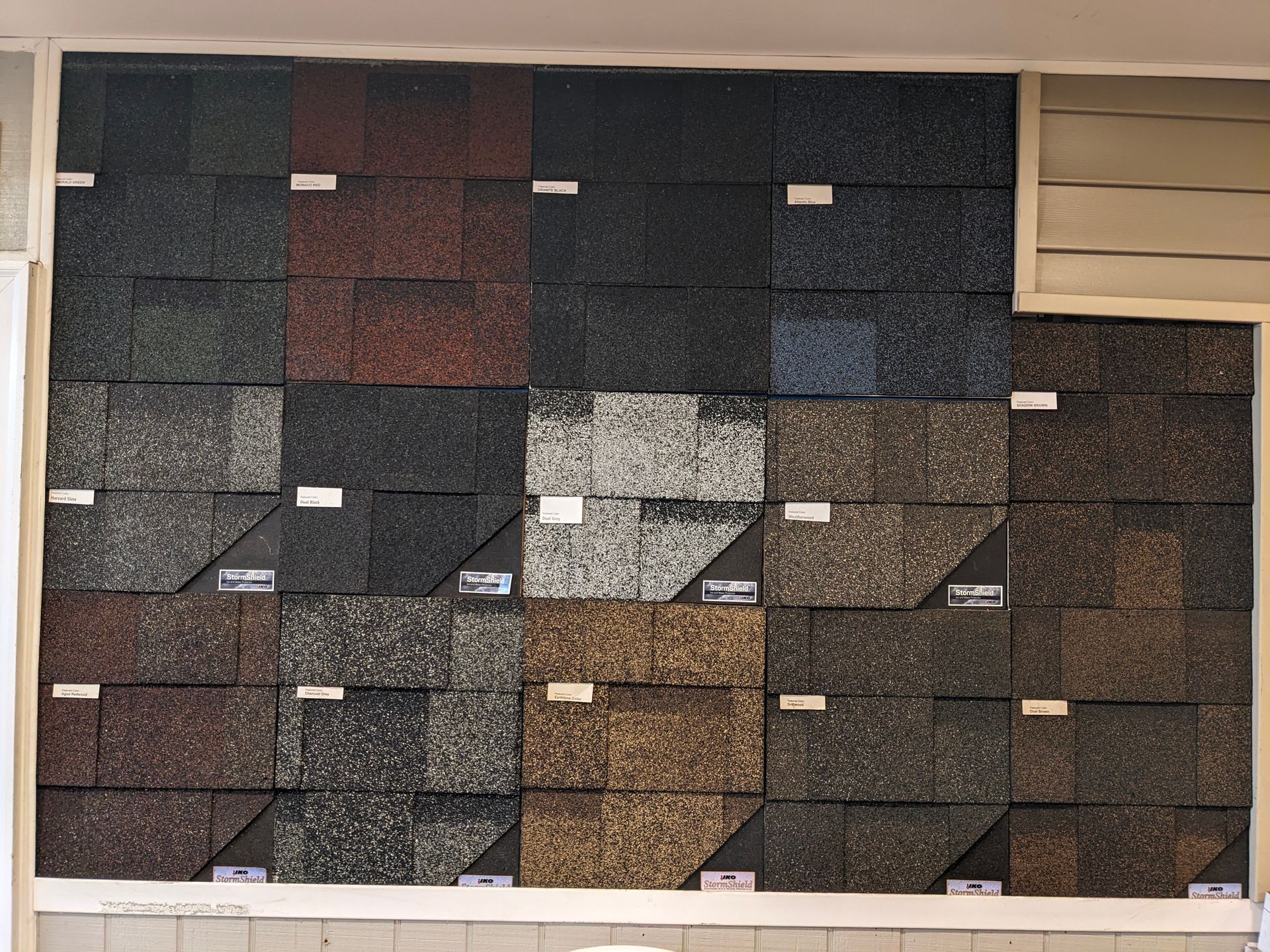 Shingle samples in various colors displayed on a wall.