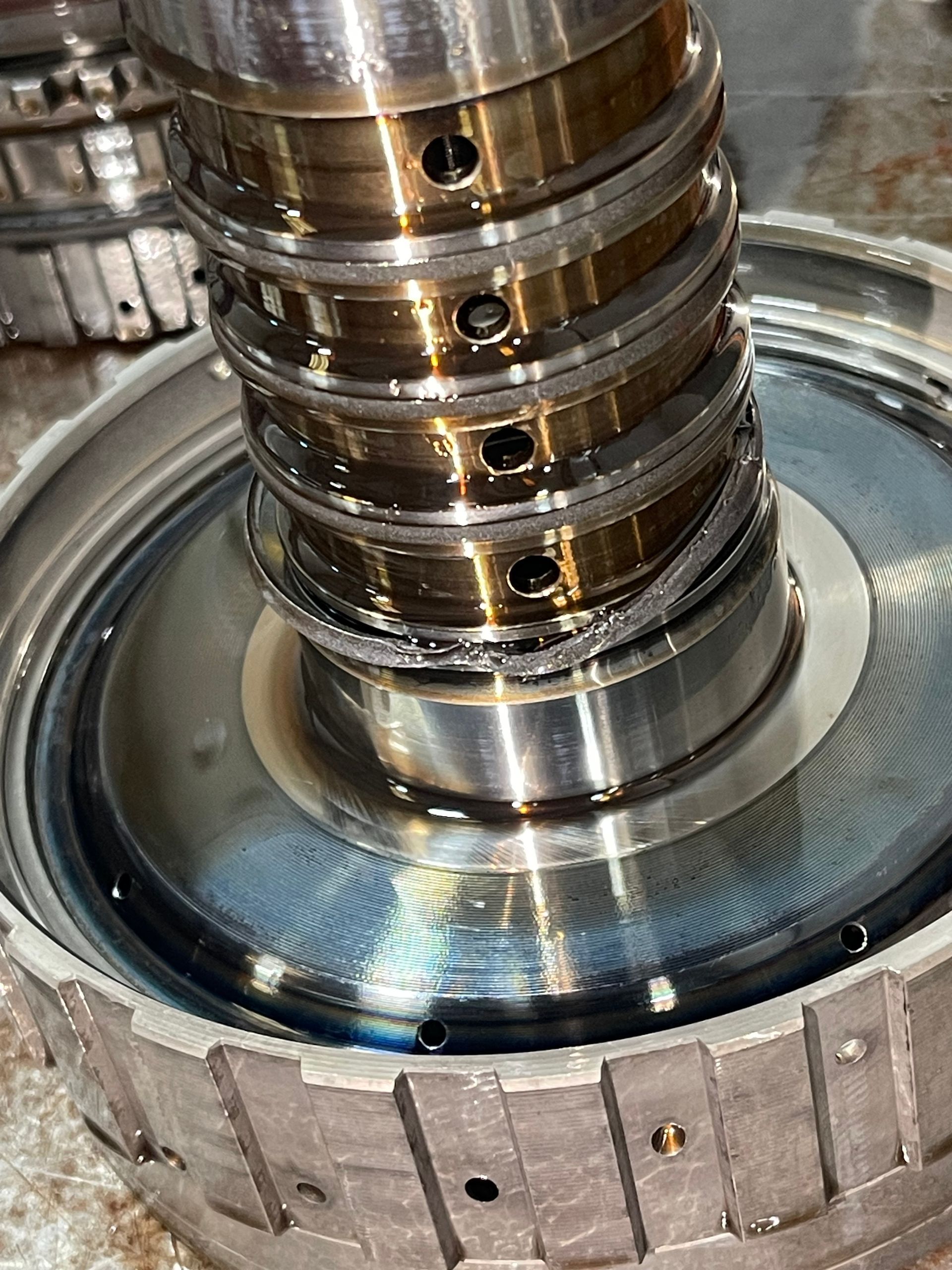 Close-up of a metal shaft with oil inside a circular machine housing