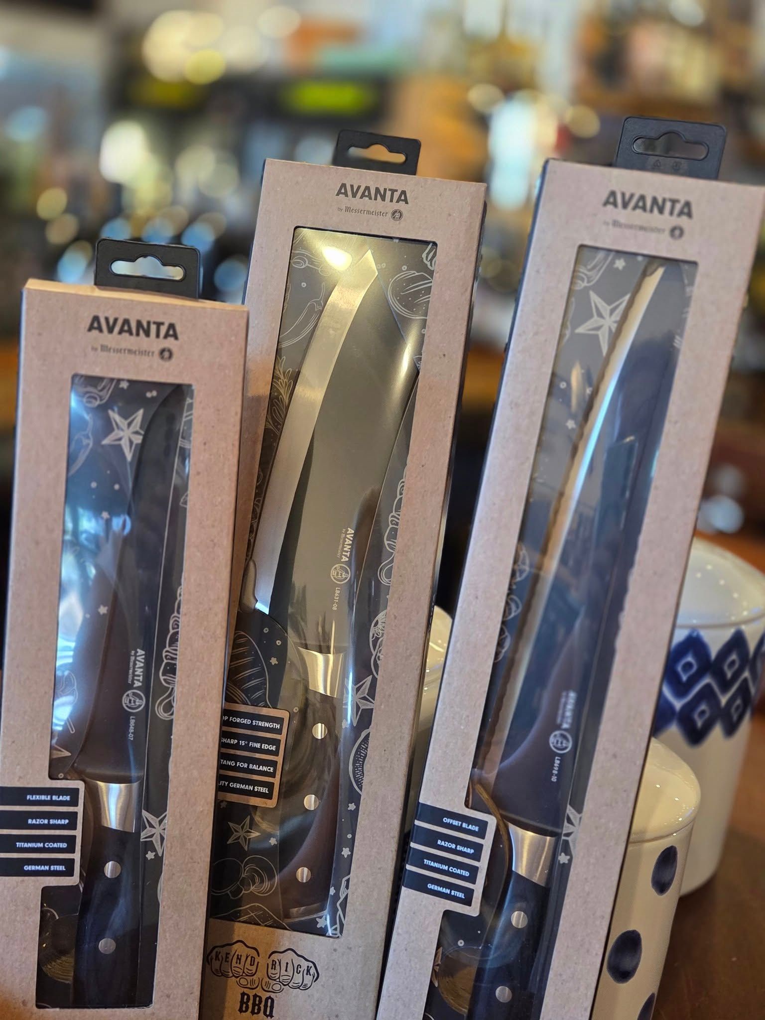 Three knives are sitting on a table in their boxes.
