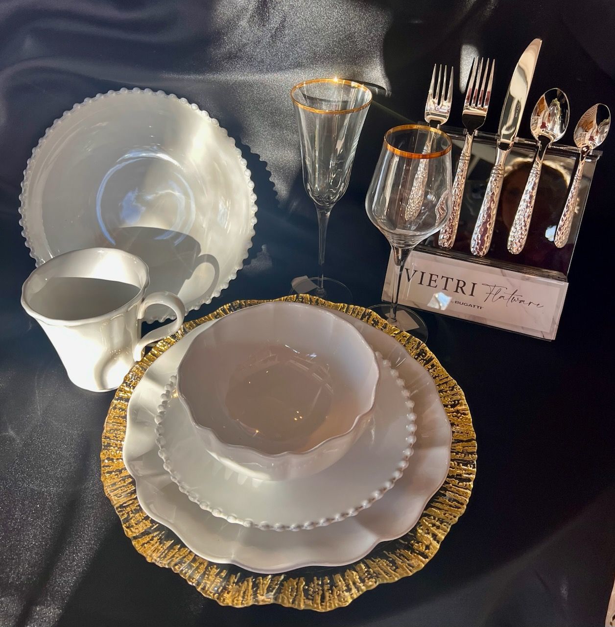 A set of white plates with gold rims and silverware on a table