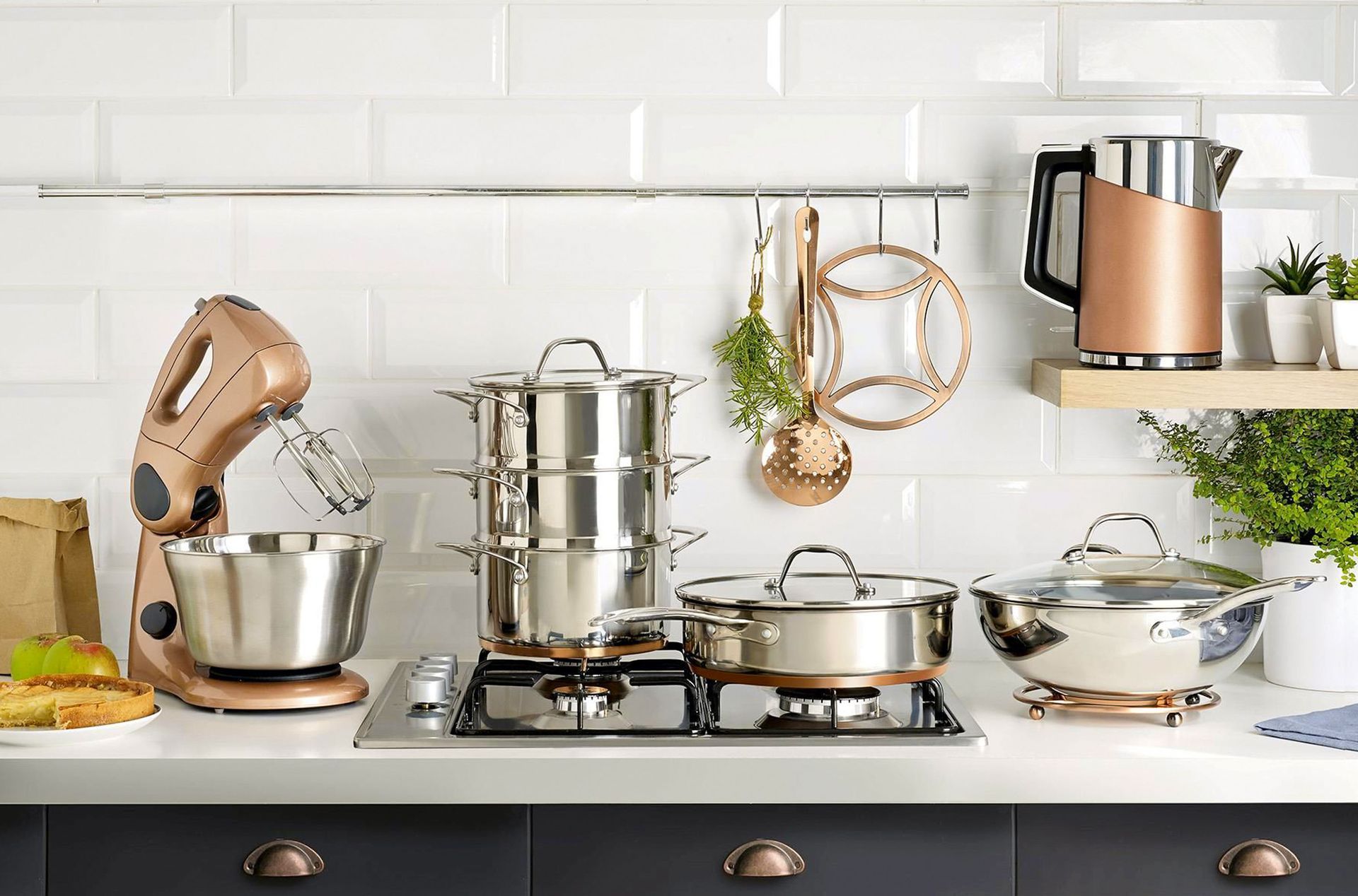 A kitchen counter with pots and pans , a mixer , and a kettle.