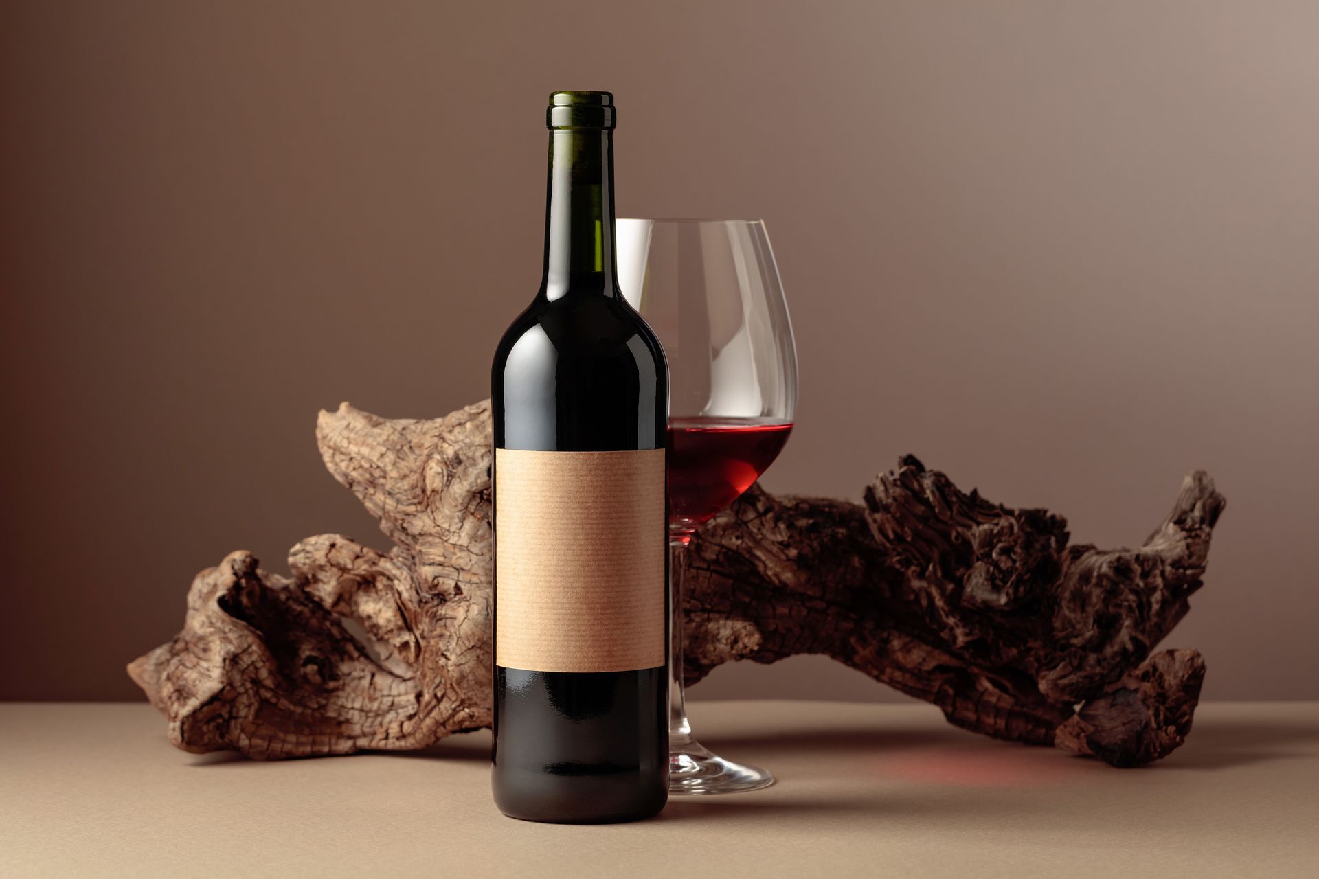 A bottle of wine and a glass of wine are on a table.