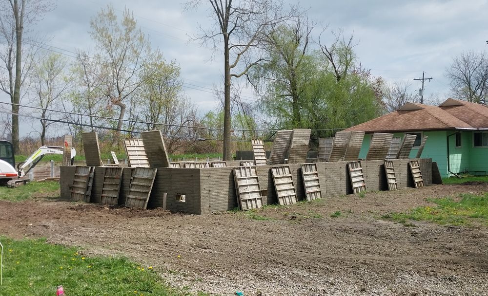A row of concrete blocks are sitting in the dirt in front of a house.