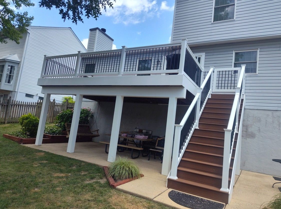 A large deck with stairs leading up to it is in the backyard of a house.