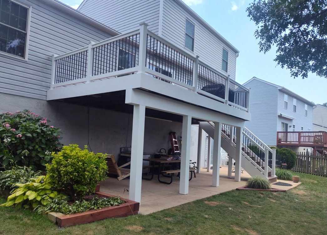 A white deck with stairs leading up to it is in the backyard of a house.