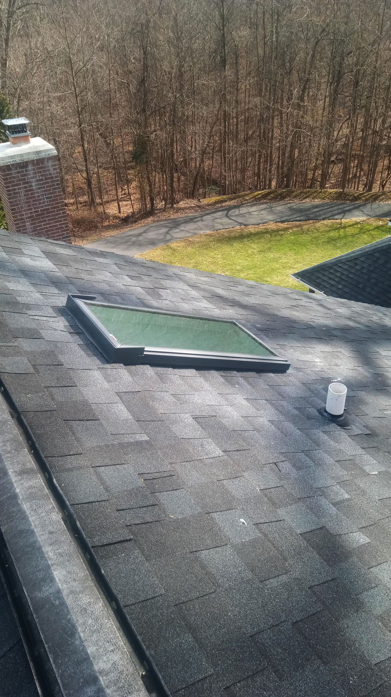 A roof with a skylight and a chimney on it.