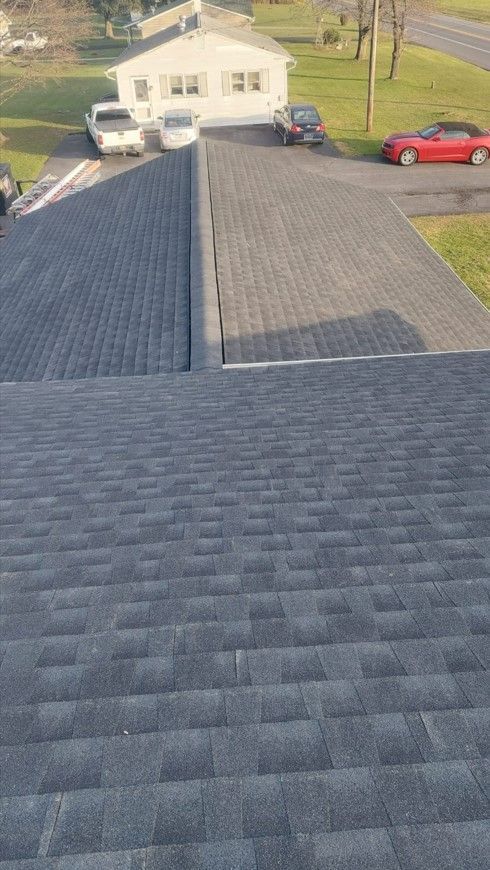 A black roof with a red car parked in front of it.