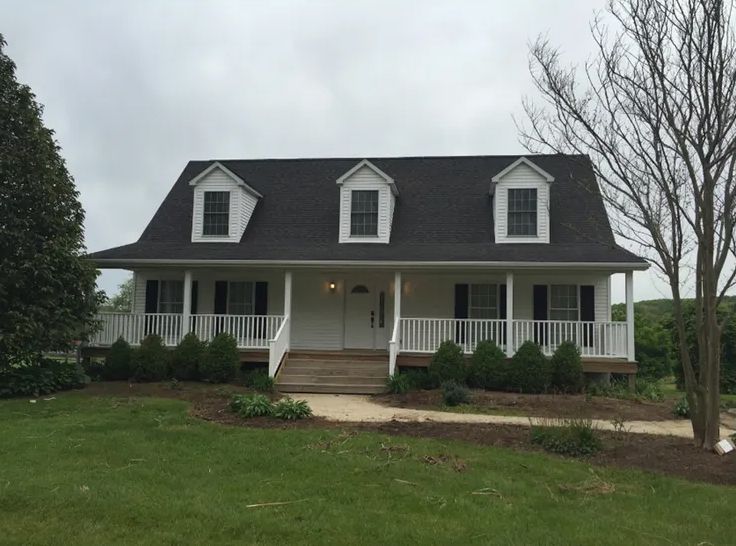 A white house with a black roof and a porch