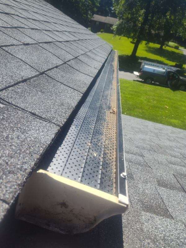 A gutter is sitting on top of a roof next to a driveway.