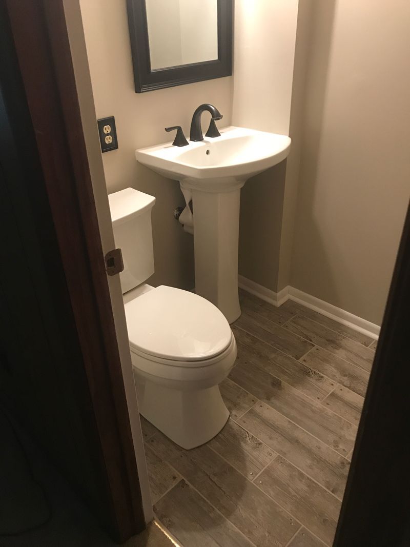 A bathroom with a toilet , sink and mirror.
