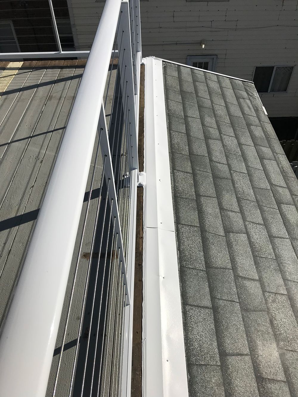 A white railing is sitting on top of a gray roof.