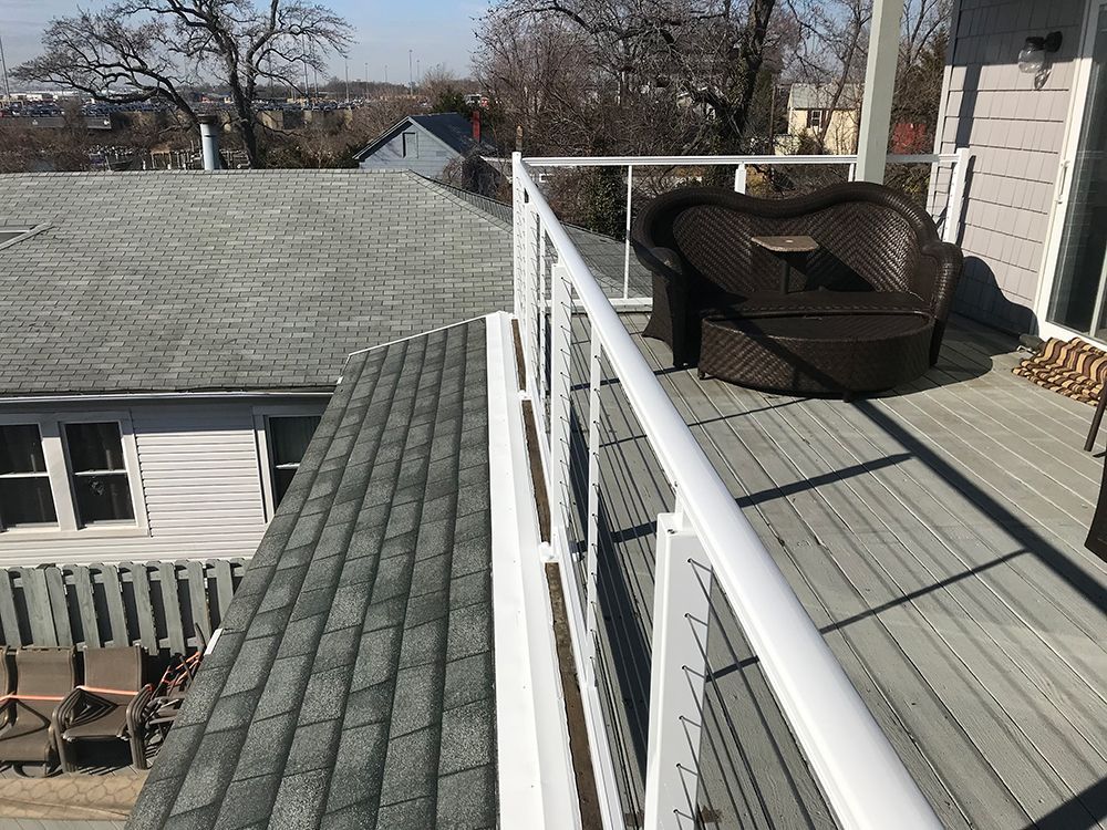 A deck with a white railing and a chair on it