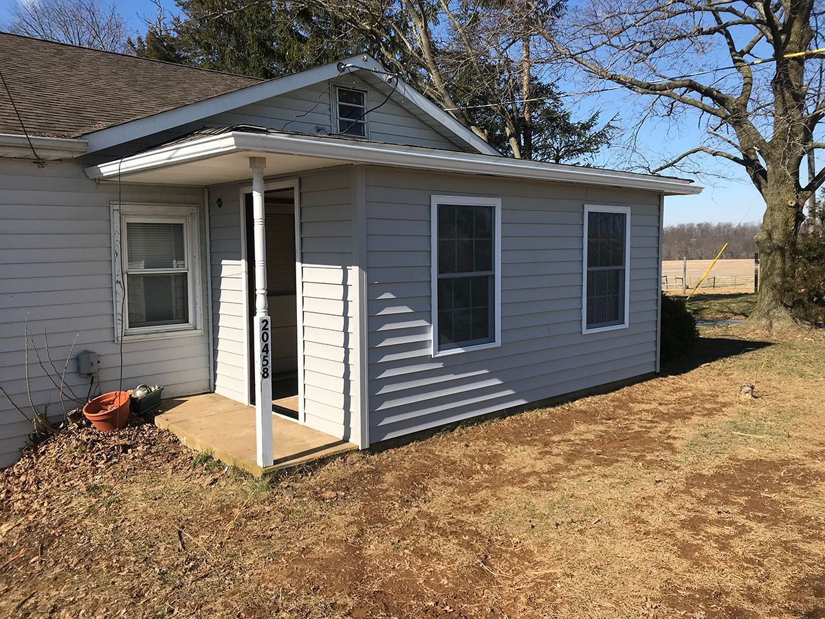 A small white house with a metal roof and a porch.