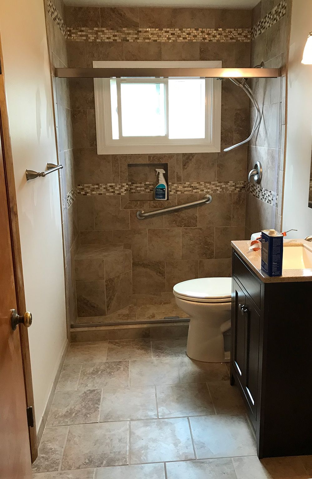 A bathroom with a toilet , sink , shower and window.
