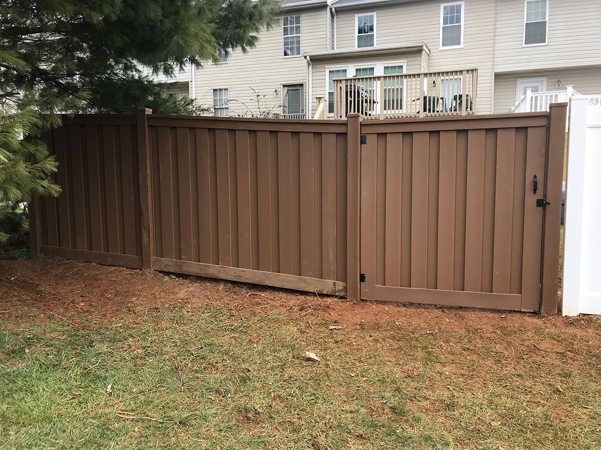 A brown wooden fence with a gate in the backyard of a house.