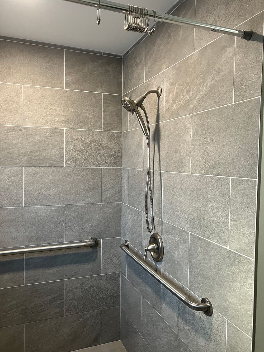 A shower with a hand rail and a shower head.