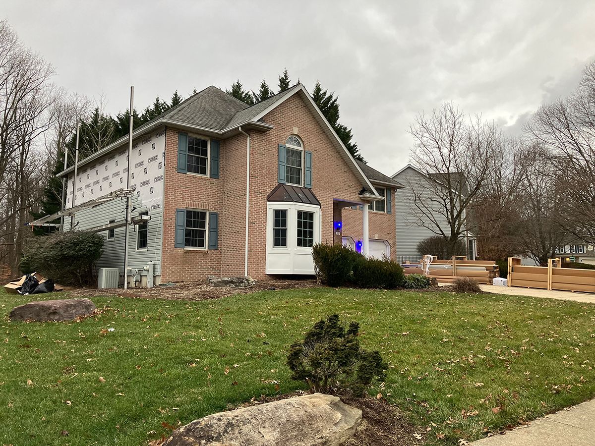 A brick house with a white door and blue shutters is being remodeled.